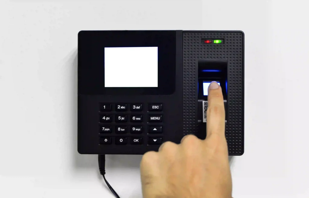 Hand entering a fingerprint for biometric authentication on a biometric access control device, illustrating biometric solutions in Kerala.
