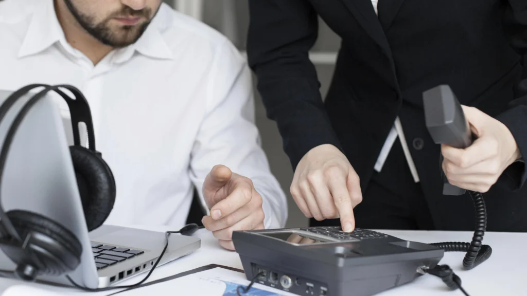 Two professionals discussing and operating an intercom device at a desk, highlighting intercom solutions in Kerala.