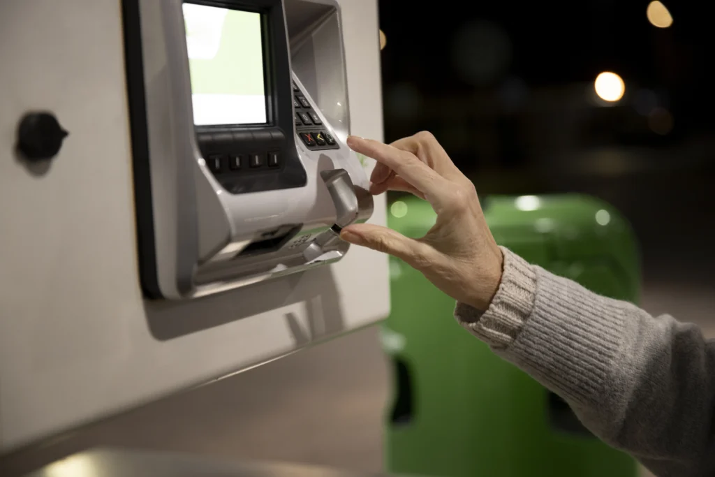 Person using an ATM with card authorization at night, illustrating biometric and bank security solutions in Kerala.