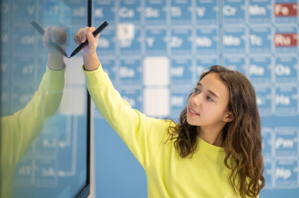 A girl interacting with a digital wall display in a smart classroom, demonstrating Smart Classroom Solutions in Kerala.