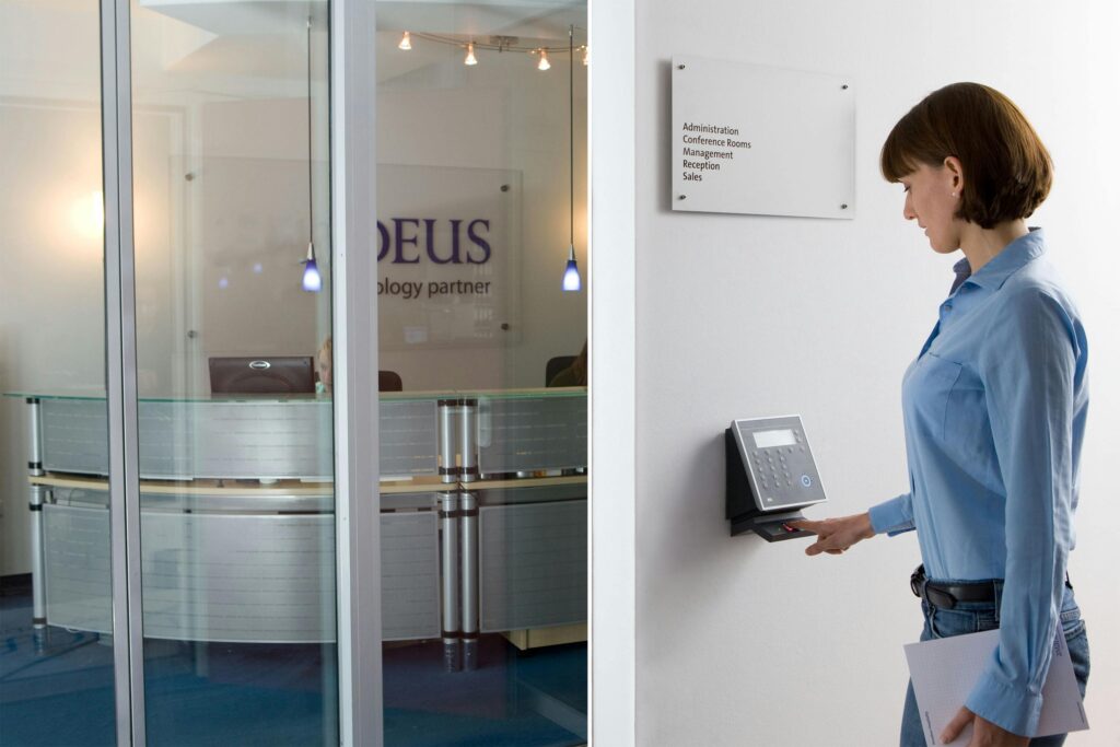 Woman using access control keypad for biometric solutions in Kerala, at an office entrance.