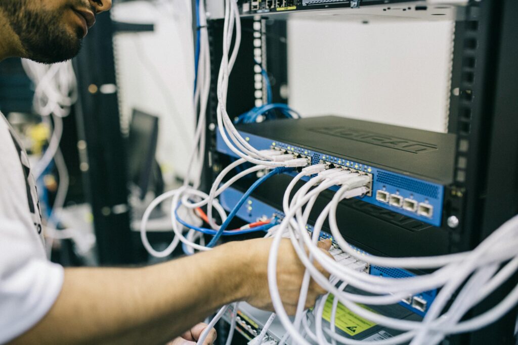 Network technician managing wiring and equipment in a server room, highlighting professional network installation services in Kerala.